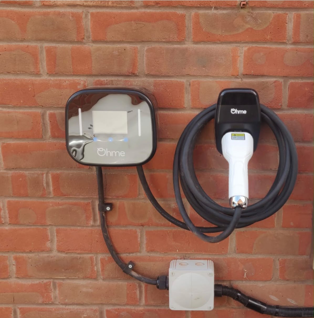 Ohme home EV charger neatly installed on a red-brick wall with tidy cable management