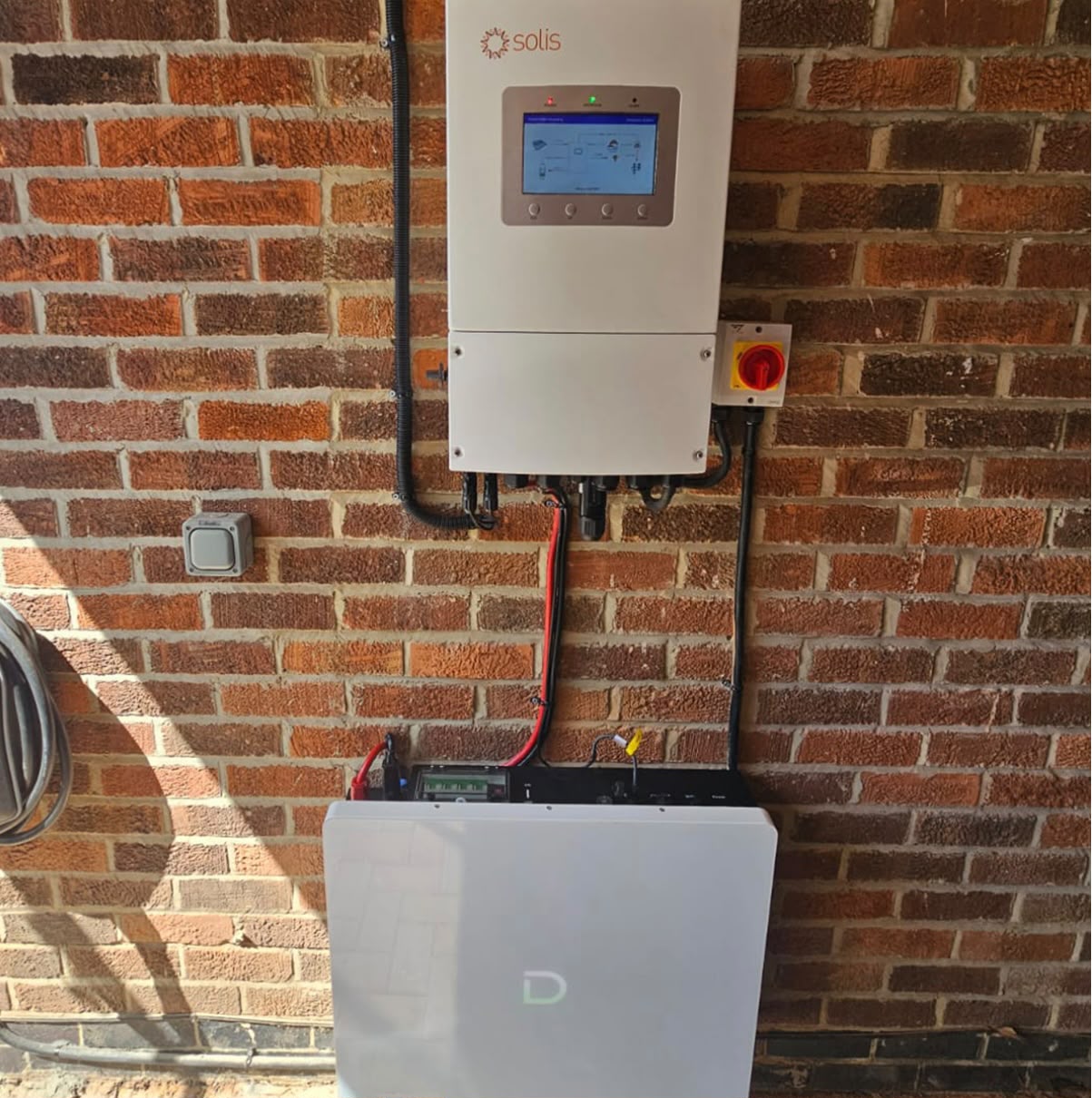 Solis inverter and single wall-mounted lithium home battery on an exterior brick wall
