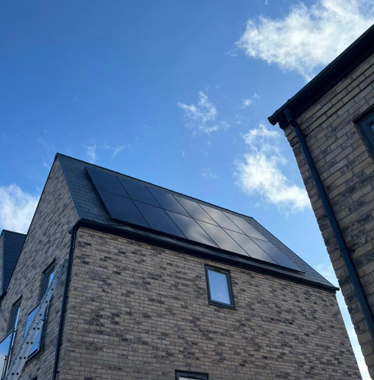 Full-black solar array on the pitched roof of a modern grey-brick home